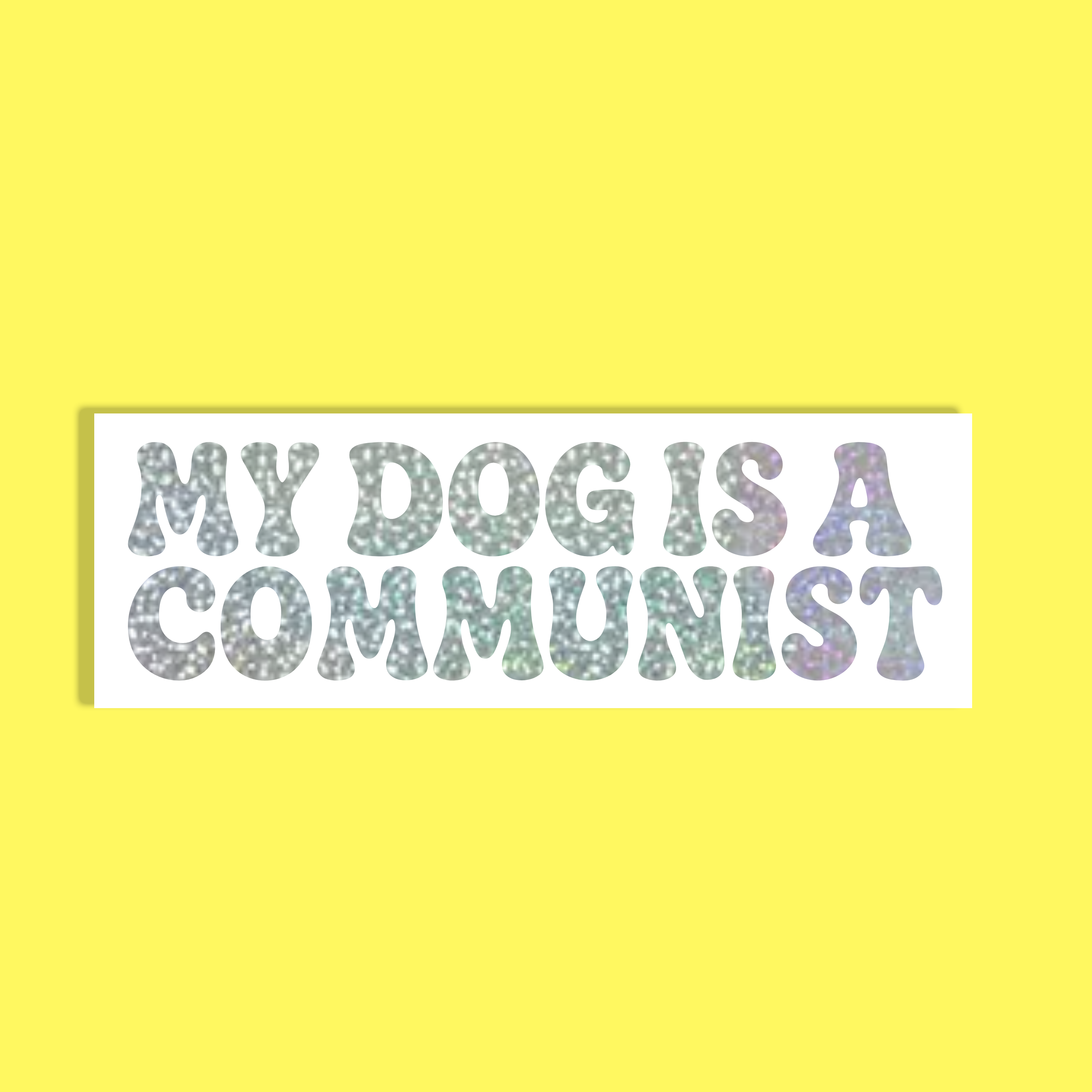 A rectangular white background with the text 'MY DOG IS A COMMUNIST' in a glittery, multicolored font, set against a solid bright yellow backdrop.