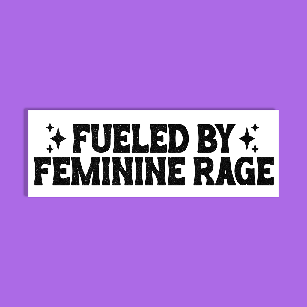 A white rectangle with bold black text reading 'FUELED BY FEMININE RAGE' and small starburst accents, centered on a solid purple background.