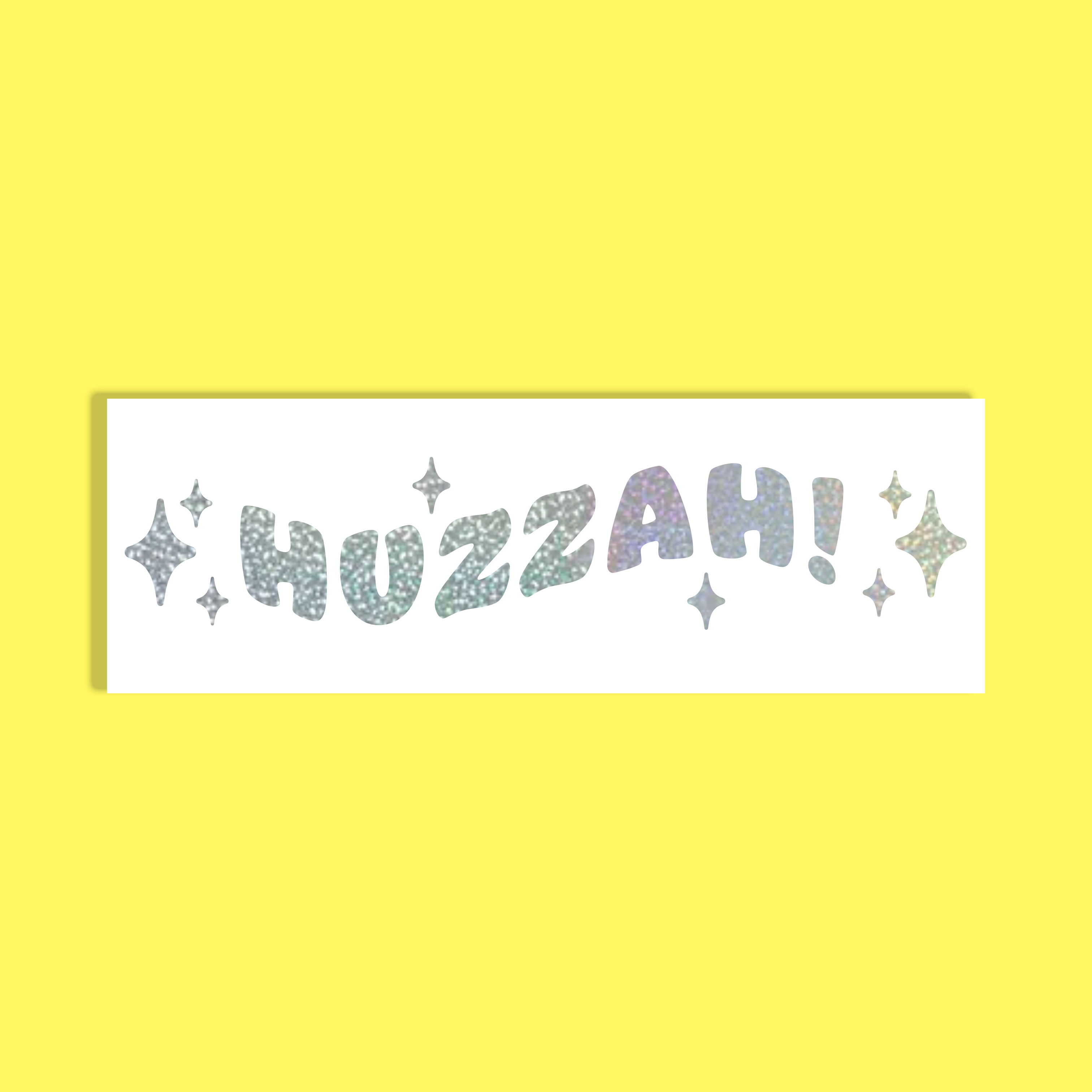 A rectangular white background featuring the word 'HUZZAH!' in silver glittery, holographic  letters with small star accents, set against a solid bright yellow background.