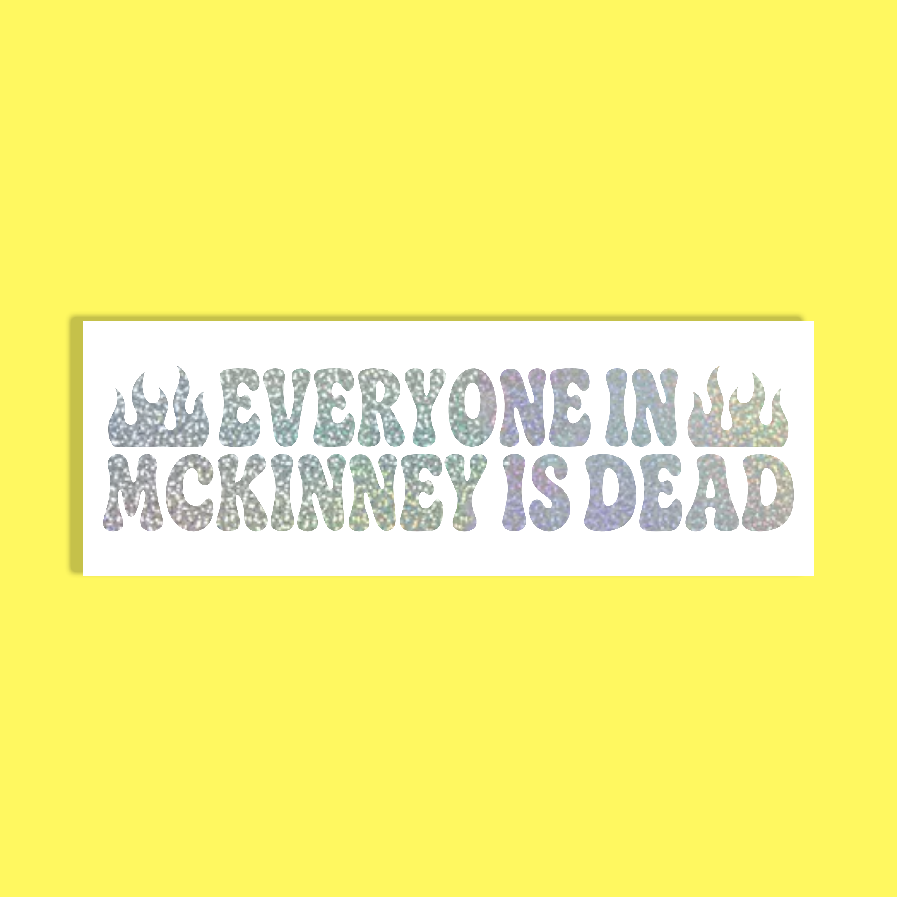 A rectangular white sticker with the text 'EVERYONE IN MCKINNEY IS DEAD' in a glittery, iridescent pastel font, flanked by two small flame icons, shown against a solid bright yellow background.