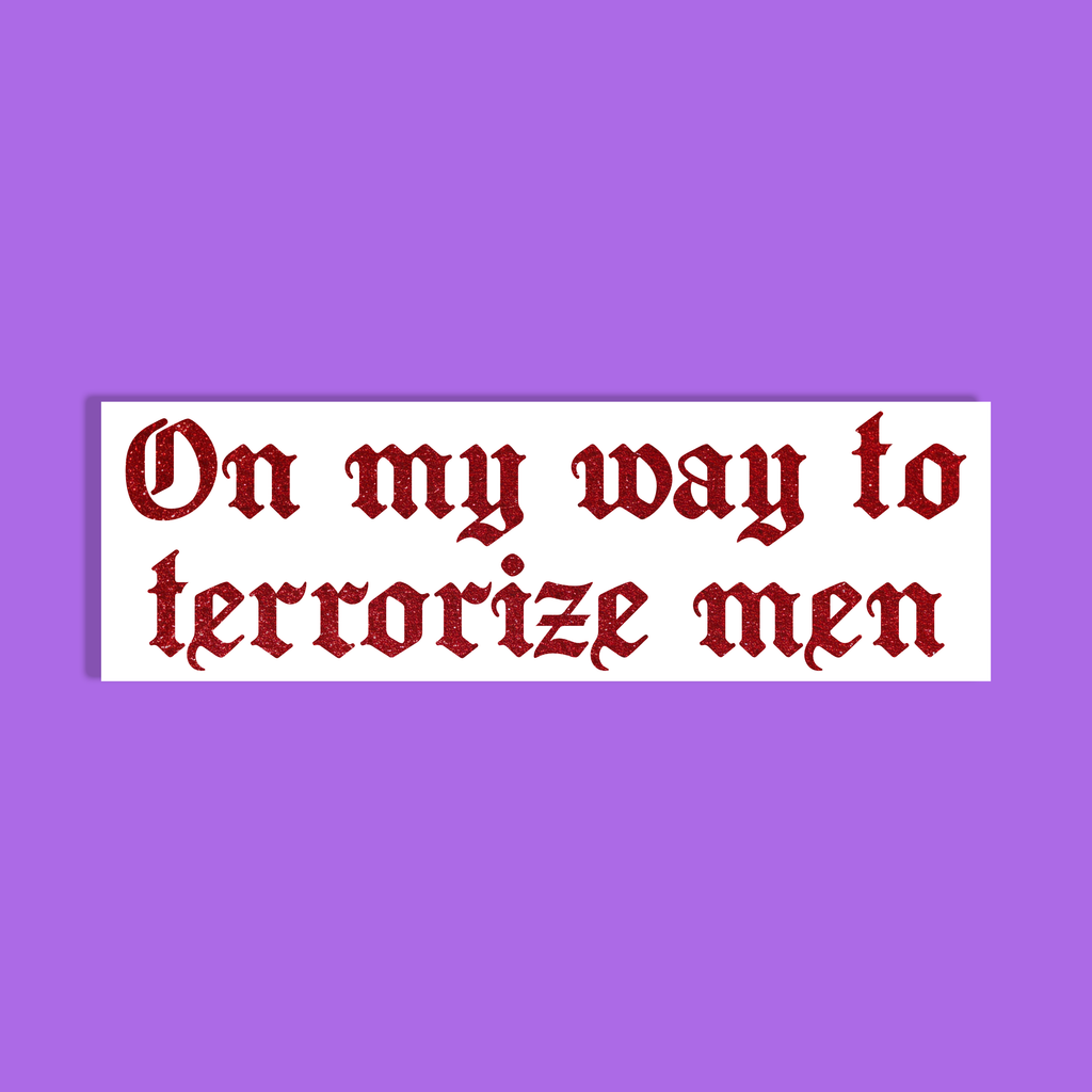 A rectangle with the phrase 'On my way to terrorize men' in a dark red glittery Gothic-style font on a white background, shown against a solid purple backdrop.
