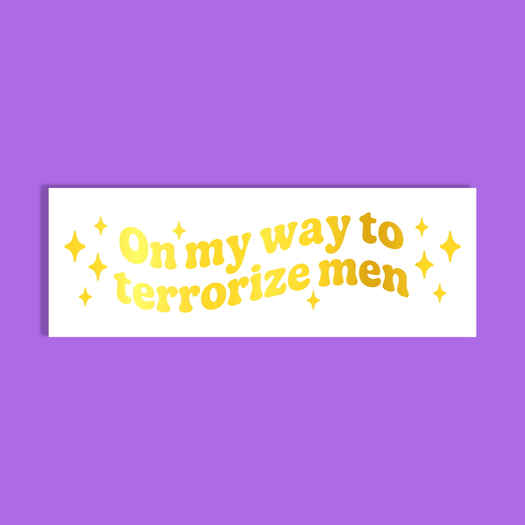 A white rectangle with gold retro-style text reading 'On my way to terrorize men' and small gold stars, shown on a solid purple background.