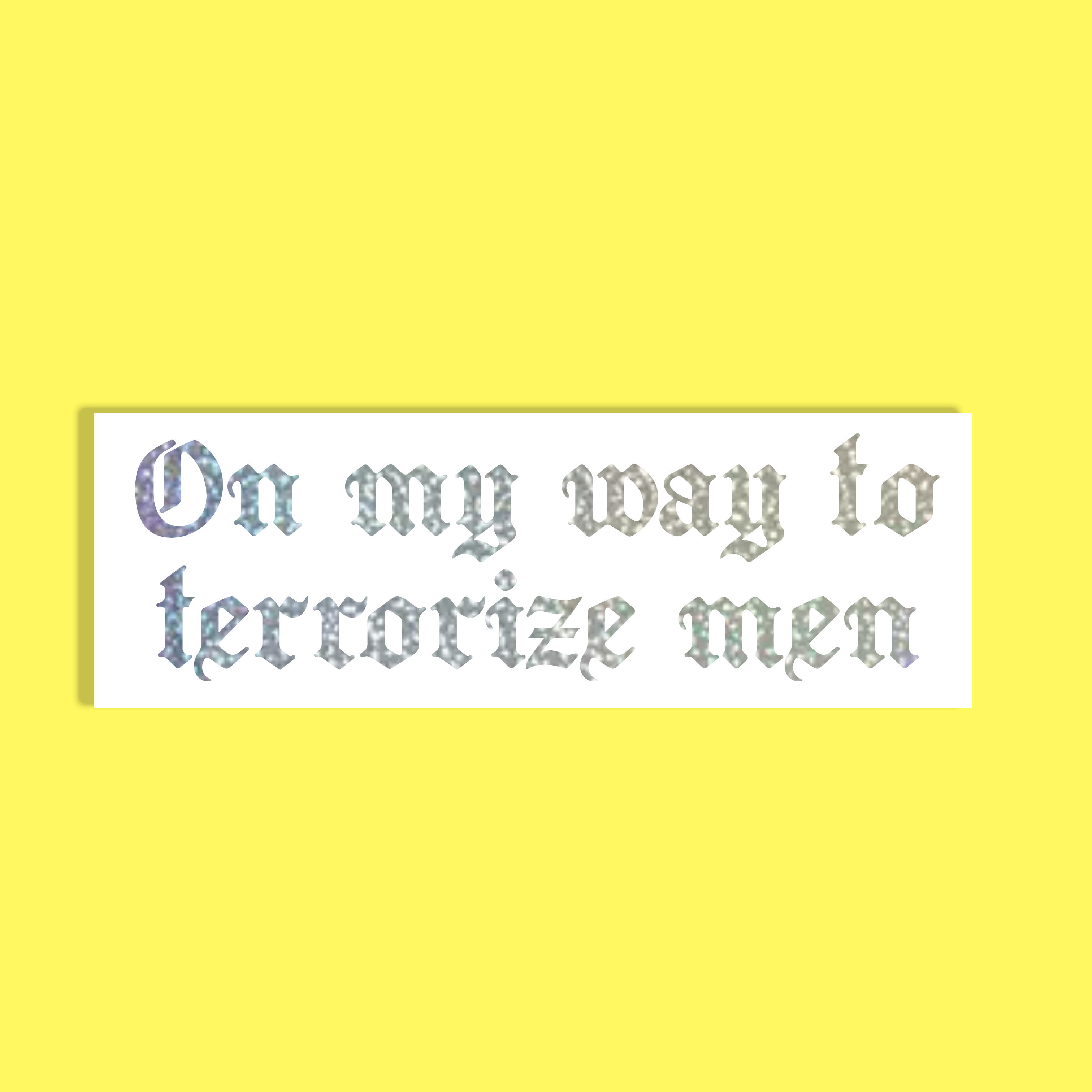 A rectangular white background with the phrase 'On my way to terrorize men' in a decorative, textured silver holographic gothic font, shown against a solid bright yellow background.