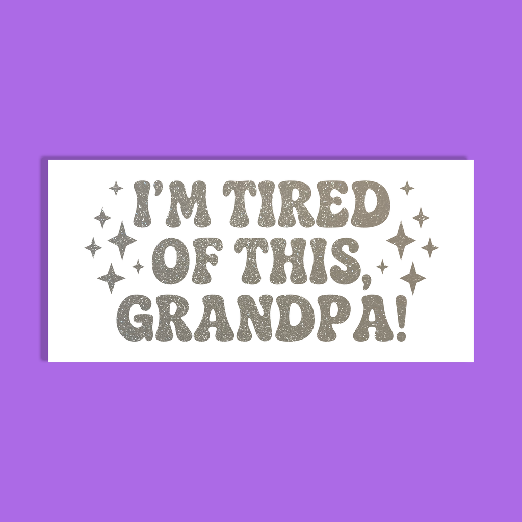 A rectangular white background with the phrase “I'M TIRED OF THIS, GRANDPA!” in glittery silver lettering, surrounded by small sparkles, shown on a solid purple background.